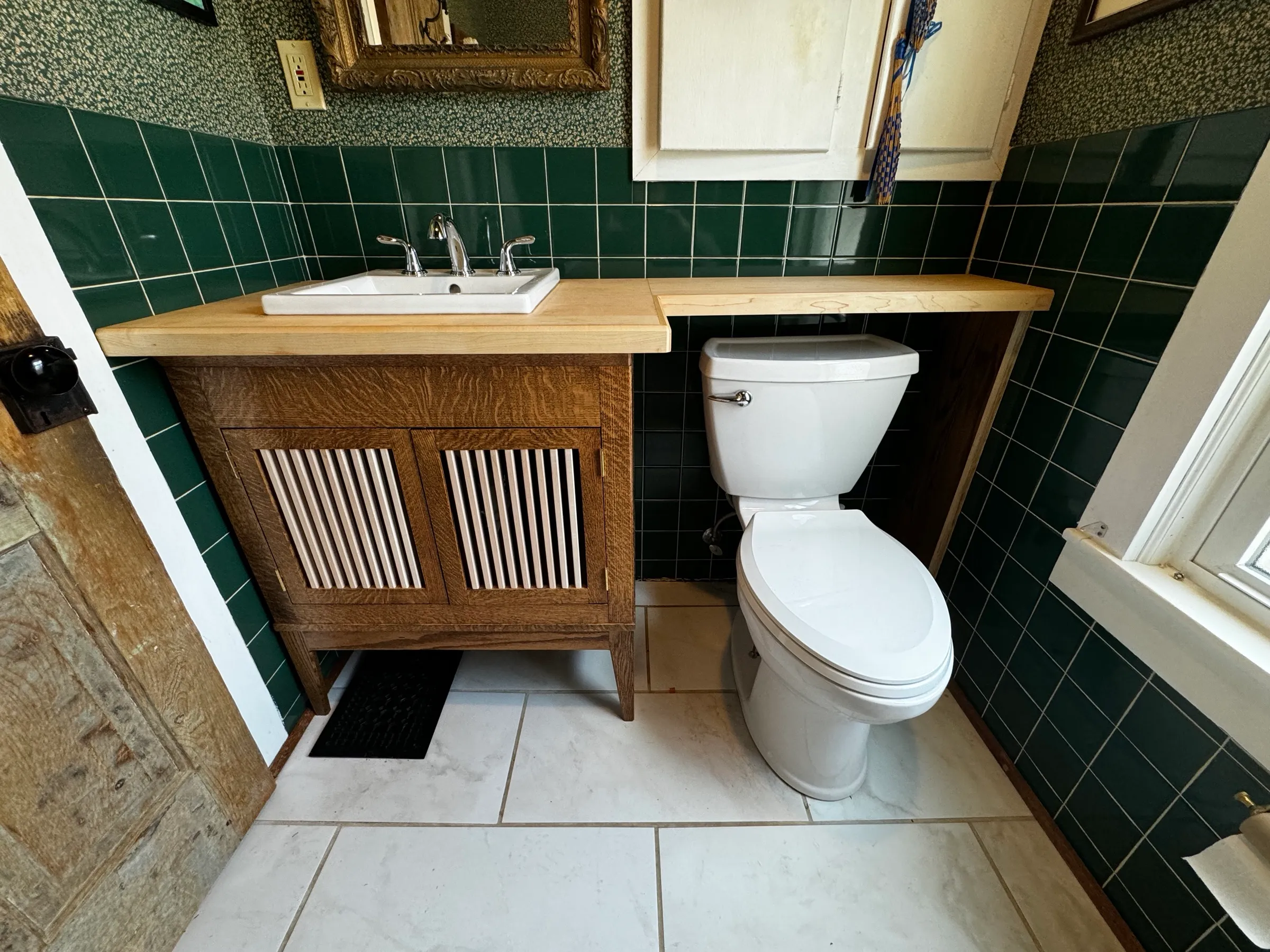 Quartersawn white oak vanity with reeded doors and a solid maple top wrapping the corner in a green-tiled bathroom, Urbana, Illinois.